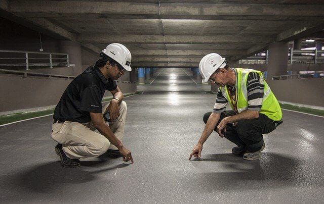 Two maintenance professionals in hard hats inspecting a commercial floor
