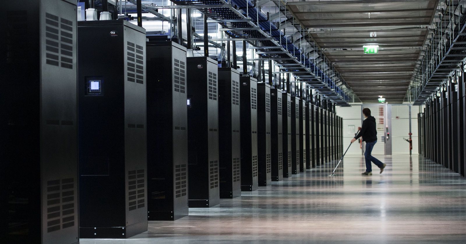 Technician cleaning a data center aisle between server racks
