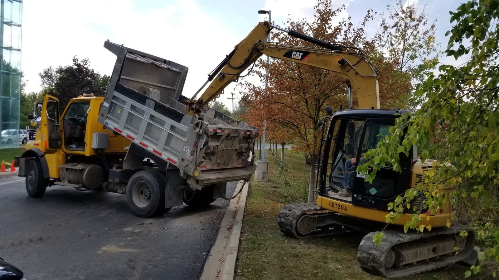 Excavator loading a dump truck with spoils during commercial excavation