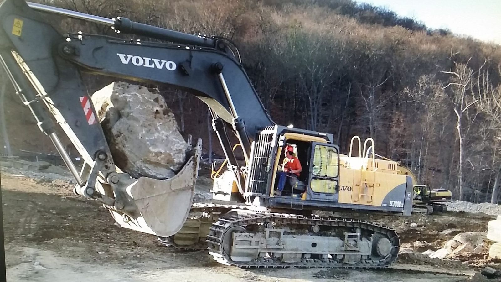 Large Volvo excavator moving rock and debris on a demolition and site-clearing job
