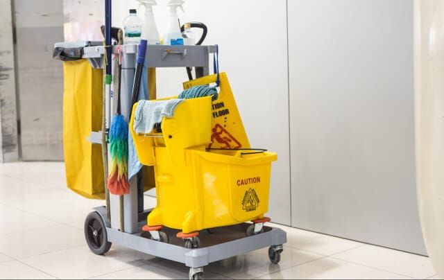 Commercial janitorial cart with mop bucket and cleaning supplies