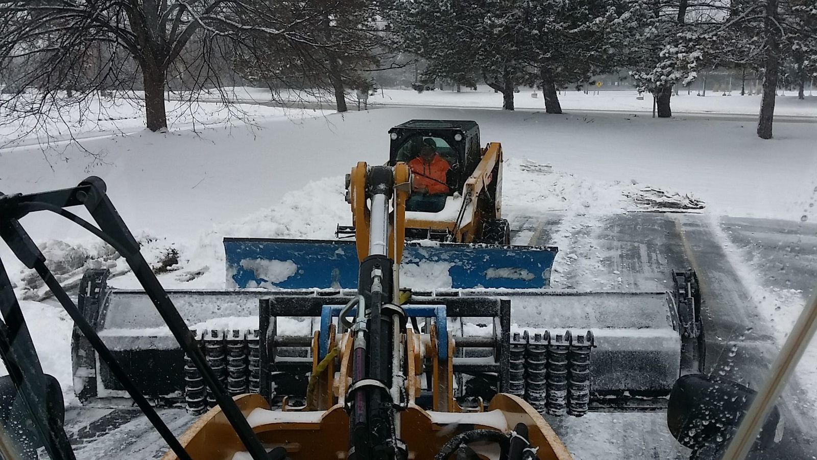 Loader with a box snow pusher clearing a parking lot after a Michigan snowfall