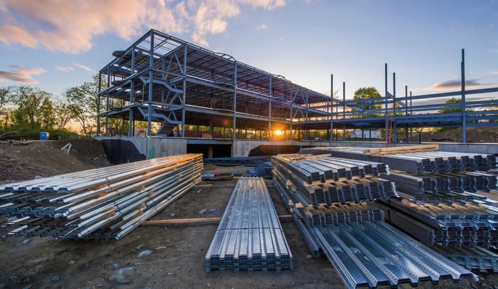Structural steel frame of a multi-story commercial building under construction at sunset